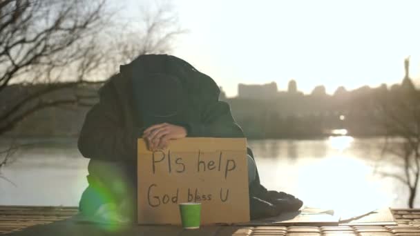 Triste mendigo sentado com a cabeça para baixo pedindo ajuda
 - Filmagem, Vídeo