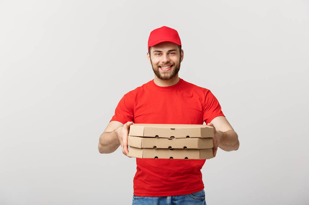 Koncepcja dostawy: Młody kaukaski przystojny dostawca pizzy gospodarstwa pudełek po pizzy na białym tle nad szarym tle - Zdjęcie, obraz