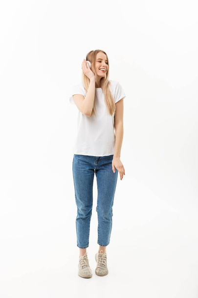 Lifestyle Concept: Portrait of a cheerful happy girl student listening to music with headphones while dancing isolated over white background - Photo, image