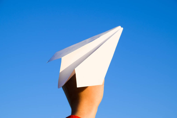 White paper airplane in hand against the sky. A symbol of freedom on the Internet - Photo, image