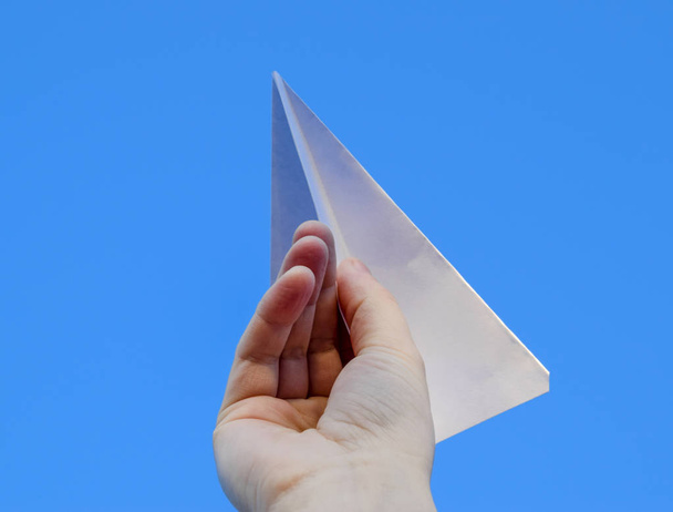 White paper airplane in hand against the sky. A symbol of freedom on the Internet - Foto, Imagen