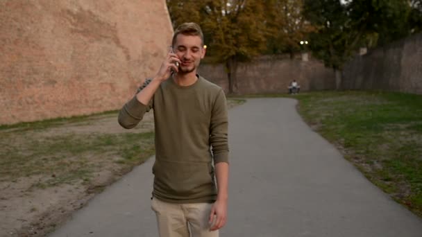 Jonge hipster met zijn slimme telefoon in het openbare park. - Video
