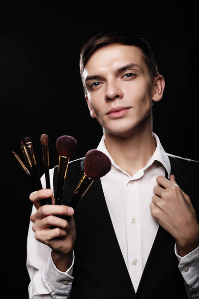 Young male make up artist posing with make-up brushes - Photo, image
