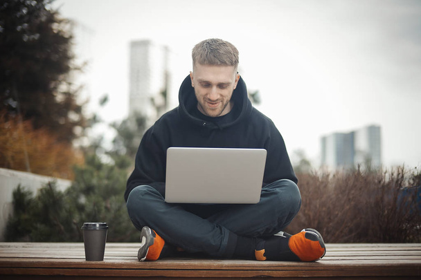 Smiling young man holding laptop on knees. - Fotografie, Obrázek