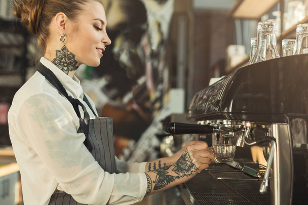 Tattooed barista making coffee in professional coffee machine - Valokuva, kuva