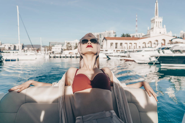 gorgeous luxury girl in sunglasses relaxes on her white yacht in the sun - Photo, image