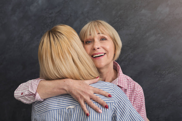 Happy adult mother and daughter embracing on grey background - Photo, Image