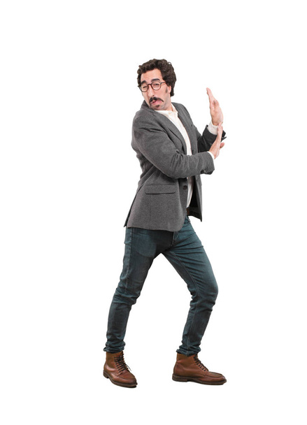 Young crazy man pushing with an empty place for your concept or object. Full body cutout person against white background. - Foto, imagen