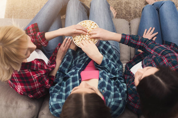 Drie vrouwen eten popcorn thuis, bovenaanzicht - Foto, afbeelding