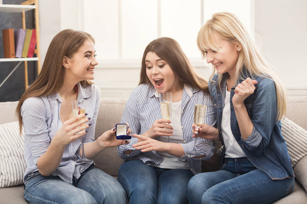 Young happy girl showing her proposal ring to surprised girlfriends - Photo, Image