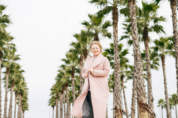 happy elegant girl in a pink coat walking in the park and laughing - Foto, afbeelding