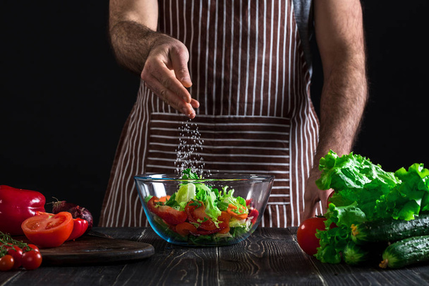 Mies valmistelee terveellistä salaattia tuoreita vihanneksia puupöydällä
. - Valokuva, kuva
