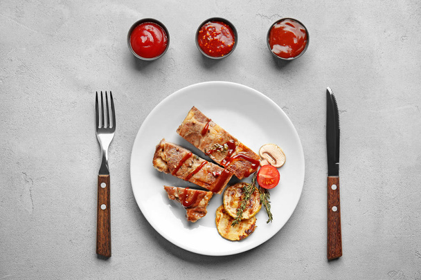 Plate of grilled meat with vegetables and barbecue sauces in bowls on table, top view - Photo, Image