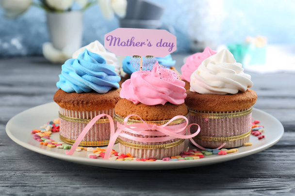 Sabrosos cupcakes y top pick con palabras DÍA DE LA MADRE en la mesa
 - Foto, Imagen