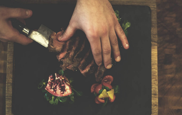 κάτοψη του χέρια του σεφ που σερβίρει μοσχαρίσιο φιλέτο - Φωτογραφία, εικόνα