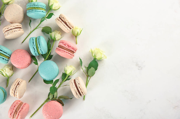 Flat lay composition with tasty macarons and roses on light background - Foto, Imagem
