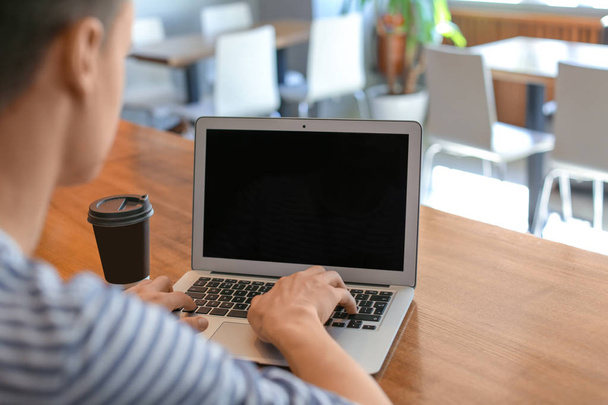 Молодий чоловік використовує ноутбук за столом у кафе
 - Фото, зображення