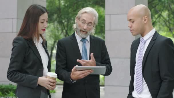 drie collectieve stafmedewerkers permanent in lobby van modern gebouw bespreken bedrijf met behulp van digitale tablet. - Video