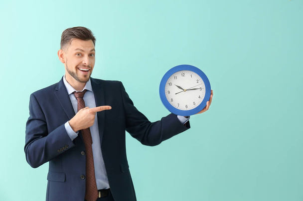 Businessman with clock on color background. Time management concept - Valokuva, kuva