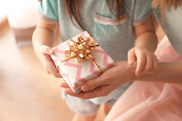Mother receiving gift from her cute little daughter at home, closeup - Photo, image