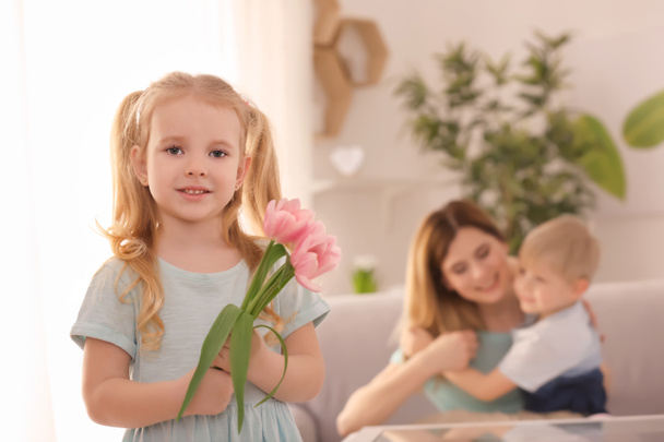 Petite fille mignonne avec des fleurs pour sa mère à la maison
 - Photo, image