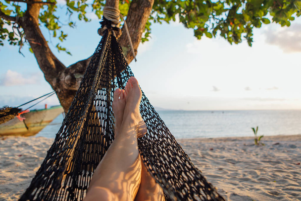 Feet of a young woman in hammock on the beach - 写真・画像