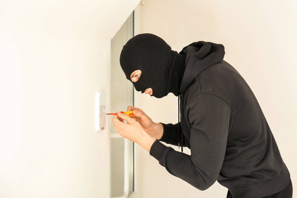 Mężczyzna złodziej łamanie zabezpieczeń systemu z śrubokręt w pomieszczeniu - Zdjęcie, obraz