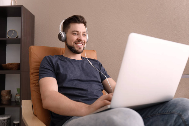 Freelancer com fones de ouvido usando laptop em casa
 - Foto, Imagem