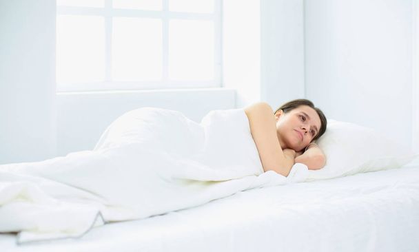 Genç güzellik beyaz bir yatakta uyuyor - Fotoğraf, Görsel