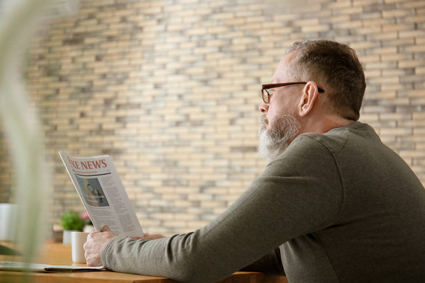 Hombre mayor leyendo el periódico en la cafetería
 - Foto, imagen