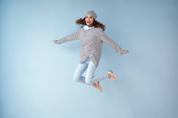 Jeune femme sautante avec écouteurs sur fond de couleur
 - Photo, image