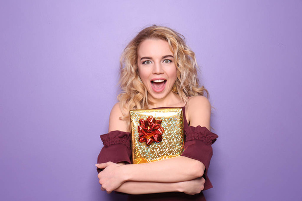 schöne junge Frau mit Geschenkbox auf farbigem Hintergrund - Foto, Bild