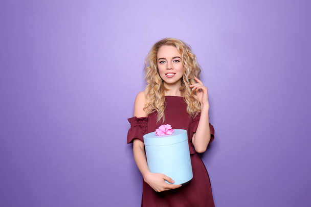 όμορφη νεαρή γυναίκα με κουτί δώρου στο φόντο χρώμα - Φωτογραφία, εικόνα