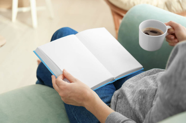 Νεαρή γυναίκα που πίνει καφέ, διαβάζοντας το βιβλίο στο σπίτι - Φωτογραφία, εικόνα