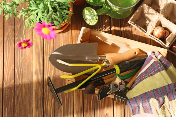 Wooden crate with gardening tools on table - 写真・画像