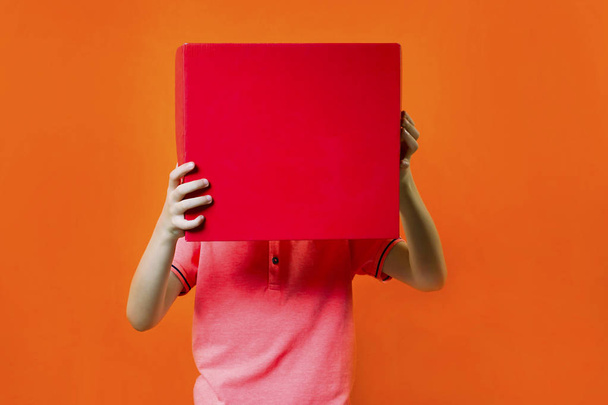 chico divertido sosteniendo una caja sobre un fondo naranja brillante
 - Foto, imagen