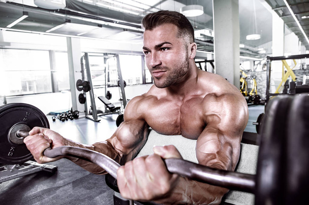 Muscular bodybuilder guy doing exercises with dumbbell - Photo, Image