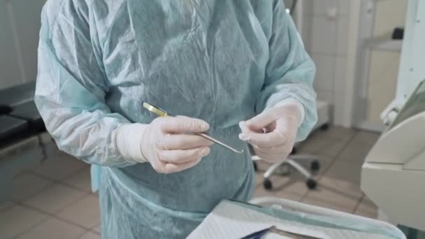 Closeup, the surgeon holds a clamp with a surgical needle in his hand, a doctor in the background wearing glasses. Sterile medical instruments in the hospital. Preparation of medical equipment before - Footage, Video