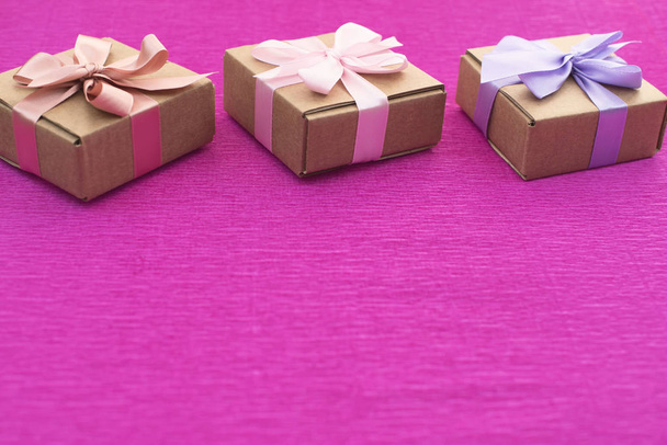 Ünnepi összetétele három Kraft dobozok, ajándékokat a világos rózsaszín háttér. - Fotó, kép