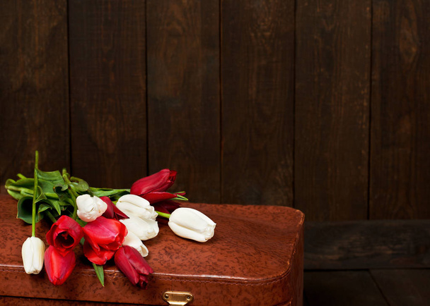 alter Koffer mit Blumen, dunklem Holzhintergrund, Retro-Konzept - Foto, Bild