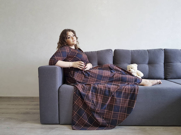 full beautiful girl on the couch sits with a cup - Фото, зображення