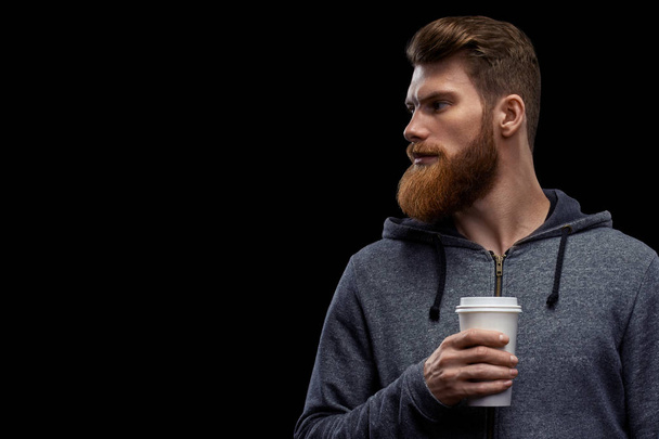 Side view of young bearded man drinking morning coffee - Foto, afbeelding