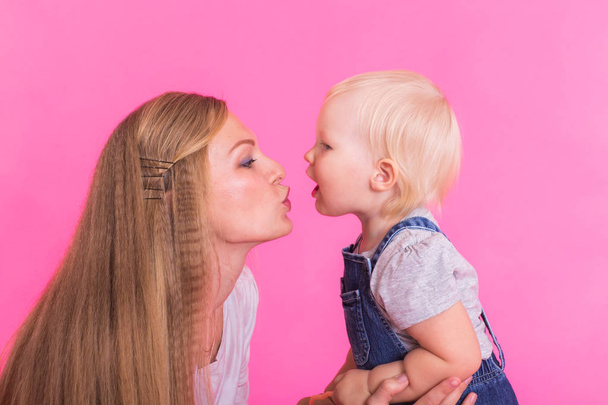 glückliches kleines Mädchen und ihre Mutter haben Spaß auf rosa Hintergrund - Foto, Bild
