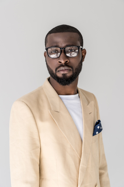 portrait of handsome stylish young african american man in eyeglasses looking at camera isolated on grey   - Foto, Imagen