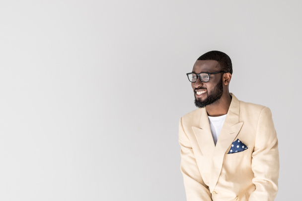 ritratto di un bel giovane afroamericano con gli occhiali che sorride e distoglie lo sguardo isolato sul grigio
 - Foto, immagini
