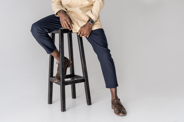 cropped shot of stylish african american man sitting on chair isolated on grey - Фото, зображення