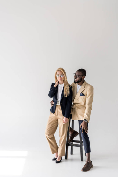 hermosa pareja multiétnica joven de moda en gafas posando juntos en gris
 - Foto, imagen