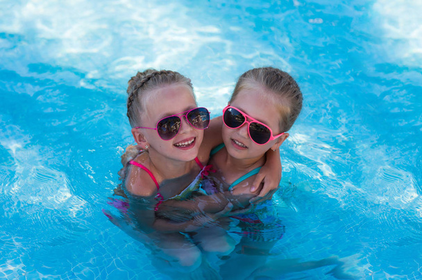 Two little funny girl in the pool on holiday - Foto, Imagen