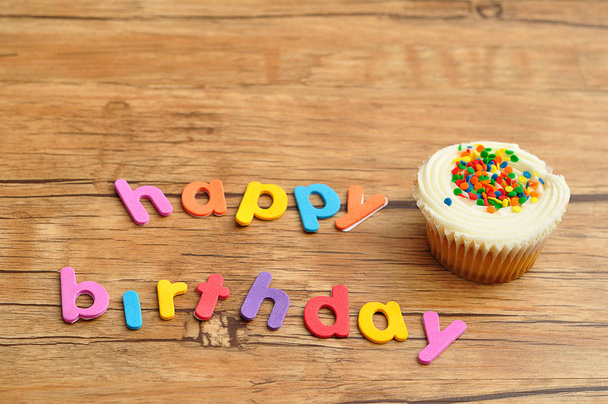 白いカップケーキとカラフルな文字にお誕生日おめでとう - 写真・画像