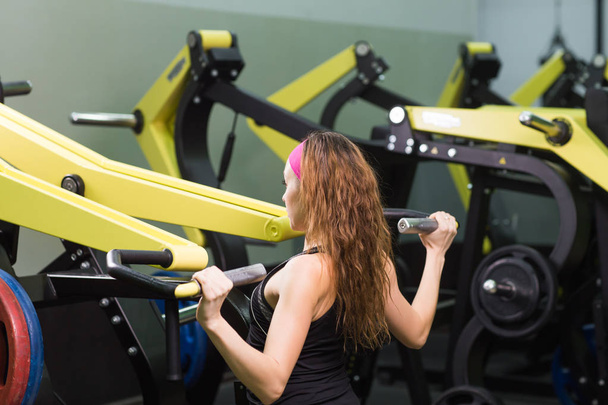 Sportschool fitnessclub overdekt met jonge vrouw opleiding, achteraanzicht - Foto, afbeelding